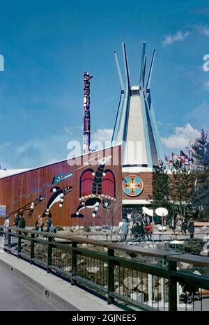 Pavillon des Indiens du Canada à Expo 67, Montréal, Québec, Canada en 1967. Le pavillon contenait des œuvres d'art et de culture autochtones ainsi que des commentaires historiques et politiques sur les questions auxquelles les peuples autochtones sont confrontés au Canada. Il y avait les peintures murales audacieuses sur les murs en bois de l'édifice peintes par l'artiste Francis Kagigewikwenikong (ici à gauche), et un totem de 65 pieds de haut sculpté par Tony et Harry Hunt de la Colombie-Britannique, dans la tradition Kwakiutl. Cette image est tirée d'une ancienne transparence couleur Kodak amateur prise par un visiteur de la foire, une photographie vintage des années 1960. Banque D'Images