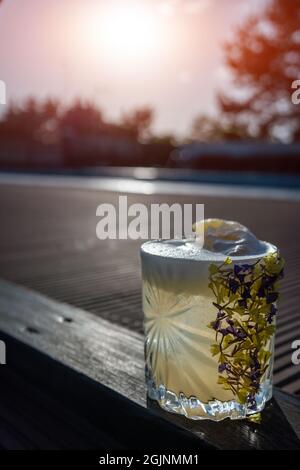 cocktail d'ananas à margarita rafraîchissant en verre garni de fleurs en plein air Banque D'Images