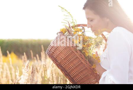 Belle femme sniffs bouquet d'herbe de fleur sur l'air libre. Copier l'espace pour le texte. Banque D'Images