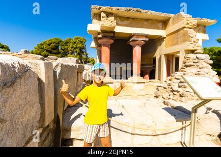 Une petite fille s'arrête pour prendre une photo d'œuvres d'art sur les murs du palais minoen à Knossos. Crète, Grèce Banque D'Images