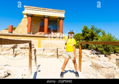 Une petite fille s'arrête pour prendre une photo d'œuvres d'art sur les murs du palais minoen à Knossos. Crète, Grèce Banque D'Images