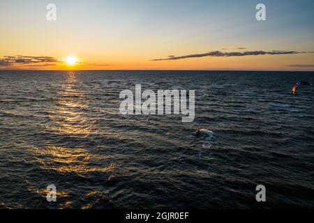 Vue aérienne majestueuse d'un jeune homme sur un scooter d'eau rapide dans les rayons d'or et reflet du soleil de coucher de soleil dans l'eau ondulée. Concept d'été, de vacances et de voyages, de sport, de vie active. Copier l'espace Banque D'Images