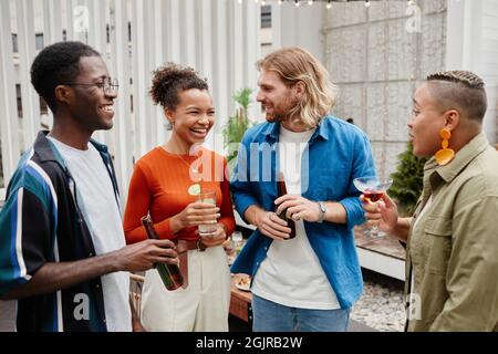 Un groupe diversifié de jeunes gens insouciants rient tout en appréciant la fête en plein air avec des amis Banque D'Images