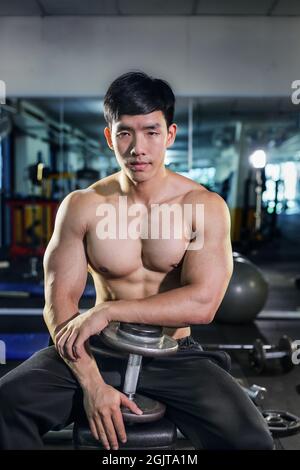 Beau asiatique avec haltères dans la salle de gym Banque D'Images