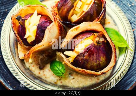Figues enveloppées de bacon frit farci de fromage. Nourriture d'automne Banque D'Images