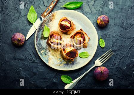 Figues farcies au fromage de chèvre cuit avec du bacon et de la sauce au yaourt grec. Banque D'Images