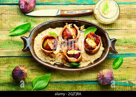 Figues farcies au fromage de chèvre cuit avec du bacon et de la sauce au yaourt grec. Banque D'Images