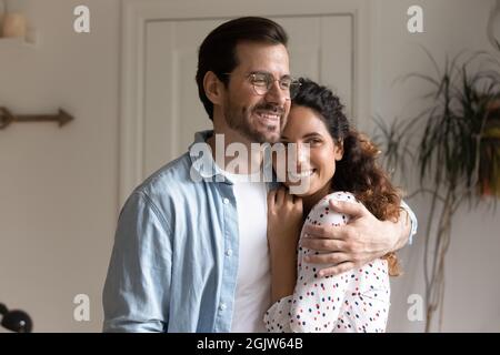 Un mari affectueux qui embrasse une femme souriant qui regarde loin Banque D'Images