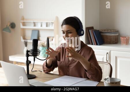 Femme indienne dans un casque parle avec un microphone professionnel par ordinateur portable Banque D'Images