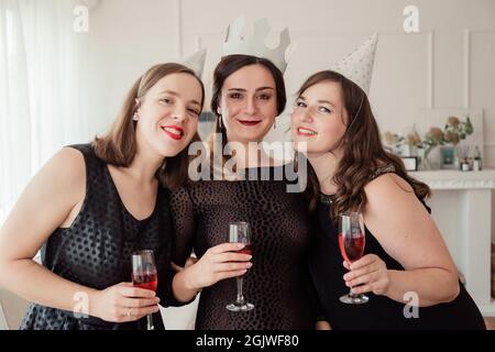 Fête des femmes. Filles filles filles dans les robes noires embrassent la fille d'anniversaire. Verres avec champagne rose dans les mains. Banque D'Images