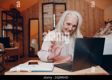 Femme d'âge mûr avec ordinateur portable assis à la table et parlant dans une tente de camping glamping. Concept moderne de mode de vie de vacances Banque D'Images