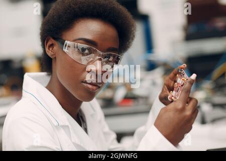 Scientifique afro-américaine femme travaillant en laboratoire avec carte électronique. Recherche et développement de dispositifs électroniques par couleur noire femme. Banque D'Images