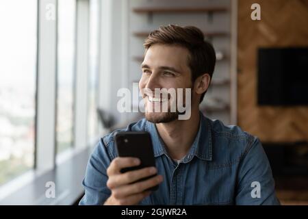 Un jeune client caucasien enthousiaste utilise un smartphone moderne Banque D'Images
