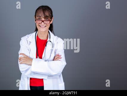 femme de 40-45 ans médecin avec des lunettes, bras croisés regardant droit devant et souriant Banque D'Images