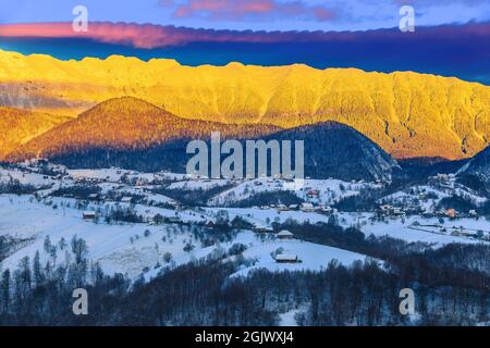 Paysage magique de l'aube d'hiver avec des montagnes enneigées spéculaires. Lever de soleil à couper le souffle et crête de montagne enneigée en arrière-plan, montagnes Piatra CRAiului, Banque D'Images