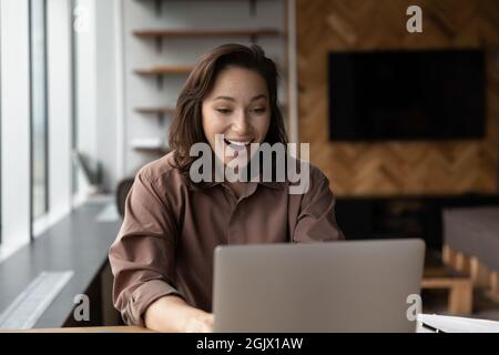 Une jeune femme excitée triomphe en lisant les nouvelles sur ordinateur Banque D'Images