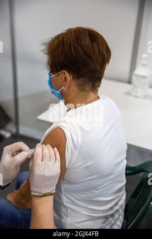 Femme d'âge moyen vaccinée par une infirmière d'homme contre le coronavirus au centre de vaccination de masse COVID -19. Banque D'Images