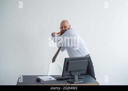Un homme d'affaires fou stressé qui a frappé son ordinateur au bureau en utilisant le concept de problème de hache. L'homme a des problèmes au travail et de la frustration. Banque D'Images