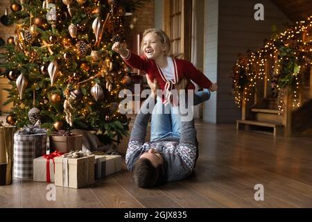 Joyeux jeune père jouant avec sa fille près de l'arbre de Noël. Banque D'Images