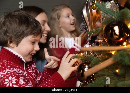 Joyeux petits enfants décorant arbre de Noël avec maman. Banque D'Images