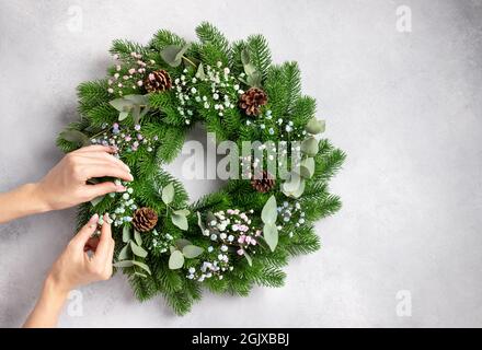 Personne mains faisant couronne de Noël. Cadeau de Noël fait soi-même Banque D'Images