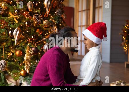 Un père et un fils ethniques souriants célèbrent Noël à la maison Banque D'Images