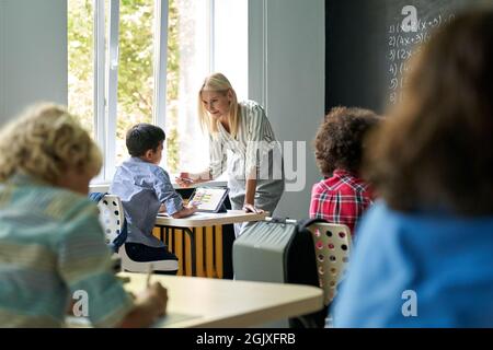 Joyeux enseignant blond expliquant les mathématiques à la leçon à l'étudiant. Concept d'éducation. Banque D'Images