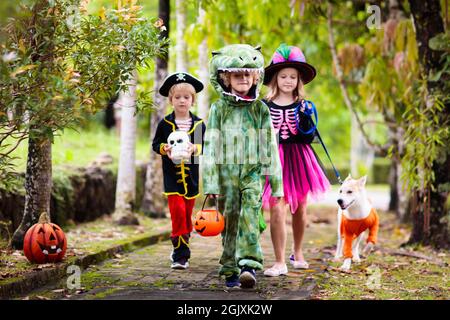 Les enfants se déguent en costume d'Halloween. Les enfants de couleur s'habillent avec un seau à bonbons dans la rue de banlieue. Petit garçon et fille trick ou traitement Banque D'Images