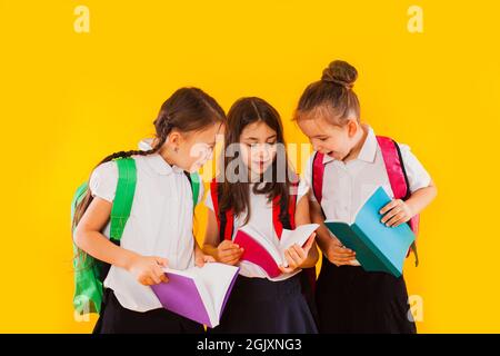 Les petites écolières lisent les livres sur fond jaune Banque D'Images