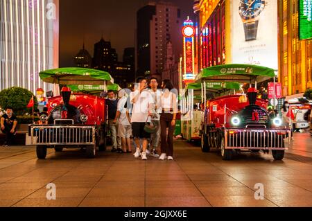 Les piétons passent les trains sur la rue piétonne Nanjing East Road dans le centre de Shanghai, en Chine, la nuit Banque D'Images