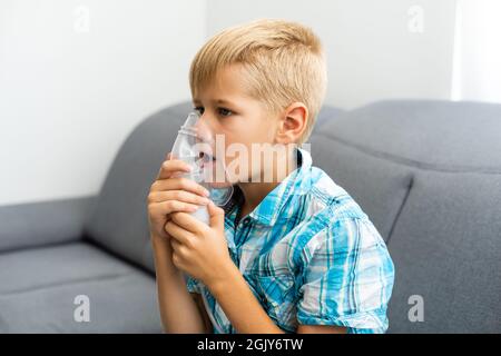 un garçon de dix ans respire par un nébuliseur. Banque D'Images