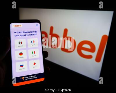 Personne tenant un téléphone portable avec le site de la société d'apprentissage de langue allemande Babbel GmbH à l'écran devant le logo. Concentrez-vous sur le centre de l'écran du téléphone. Banque D'Images