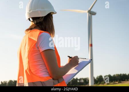 L'ingénieur de maintenance féminin contrôle le travail des éoliennes et des éoliennes. Technologie des énergies renouvelables. Production d'électricité verte. Banque D'Images