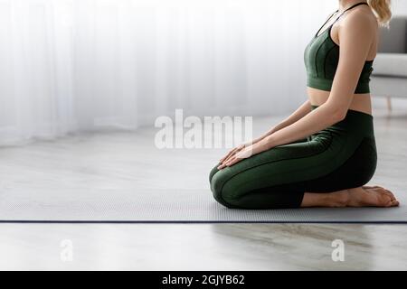 Calme méconnaissable femme millénaire caucasienne pratiquant seul le yoga, assise sur un tapis à la maison Banque D'Images
