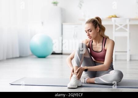 Dépression jeune femme blonde caucasienne souffrant de douleur, se sentant mal dans sa jambe après l'entraînement Banque D'Images