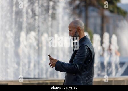 Russie Saint-Pétersbourg 09.09.2021 Un homme prend des photos sur un smartphone dans un parc de la ville. Photo de haute qualité Banque D'Images