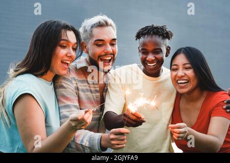 Divers amis s'amusent à célébrer avec des feux d'artifice - concentrez-vous sur les mains droites tenant des spameurs Banque D'Images