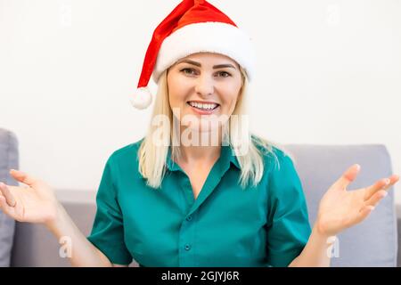 Portrait de tête souriante femme agitant la main, saluant des amis ou de la famille, regardant l'appareil photo, faisant appel vidéo sur fond d'arbre de Noël, heureux Banque D'Images