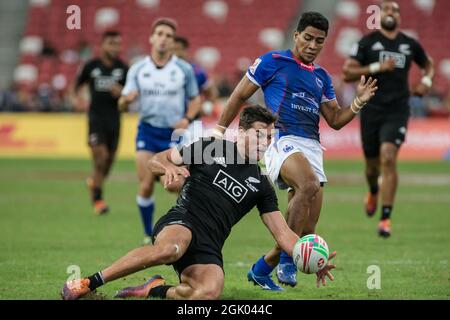 SINGAPOUR-AVRIL 14 : Andrew Knewstub de l'équipe des 7 de Nouvelle-Zélande (gauche/noir) joue contre un joueur de l'équipe des 7 de Samoa (bleu) pendant le 2e jour de HSBC World Rugby Singapore Sevens le 14 avril 2019 au stade national de Singapour Banque D'Images