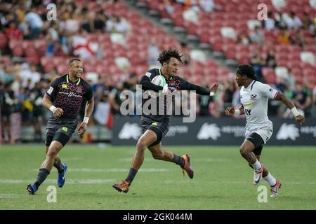 SINGAPOUR-AVRIL 14 : Ryan Olofofela de l'équipe d'Angleterre 7s (milieu/bleu) en action contre l'équipe de Carlin Isles des Etats-Unis 7s (blanc) lors du match de médaille de bronze de HSBC World Rugby Singapore Sevens le 14 avril 2019 au stade national de Singapour Banque D'Images