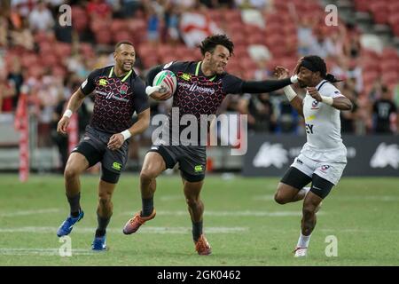 SINGAPOUR-AVRIL 14 : Ryan Olofofela de l'équipe d'Angleterre 7s (milieu/bleu) en action contre l'équipe de Carlin Isles des Etats-Unis 7s (blanc) lors du match de médaille de bronze de HSBC World Rugby Singapore Sevens le 14 avril 2019 au stade national de Singapour Banque D'Images