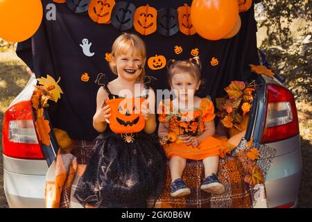 Enfants célébrant Halloween dans le coffre de la voiture. Amis enfants filles se préparant pour les vacances d'octobre en plein air. Trick ou tronc Banque D'Images