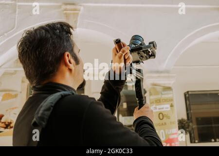 Le caméraman masculin photographie l'architecture urbaine et les façades de bâtiments avec Steadicam sur un appareil photo sans miroir. Fond de la Grèce ou de l'Italie. Banque D'Images