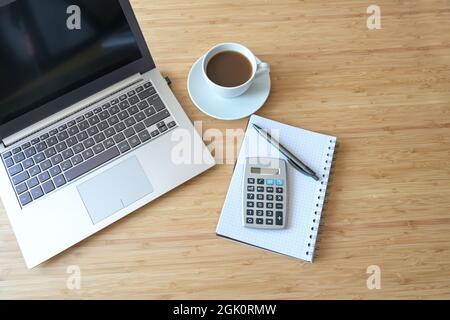 Ordinateur portable, calculatrice, livre en spirale et café, plat sur un bureau en bois, concept de comptabilité d'affaires, vue de dessus, espace de copie, foc sélectionné Banque D'Images