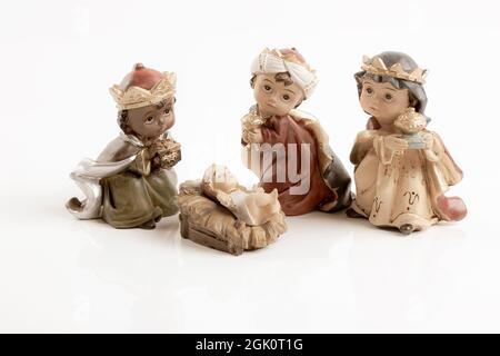 Les trois garçons sages et le bébé Jésus. Concept du jour de l'Epiphanie heureux. Figurines en céramique isolées sur fond blanc. Carte de vœux. Banque D'Images