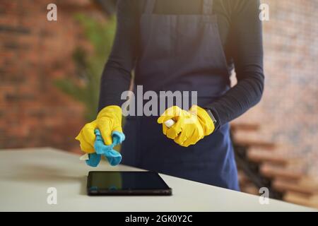 Dose de produit nettoyant en gants de caoutchouc et uniforme à l'aide d'un spray désinfectant antibactérien et d'un chiffon en microfibre tout en désinfectant le Banque D'Images