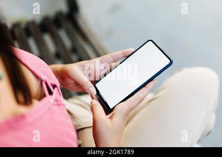 Image de maquette d'une femme tenant un smartphone avec un écran vide à l'extérieur Banque D'Images