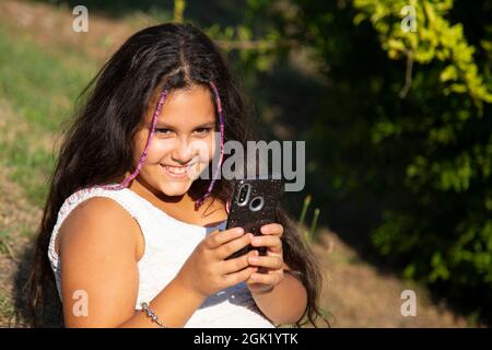 gypsy fille avec de longs cheveux noirs prend des selfies avec son smartphone Banque D'Images