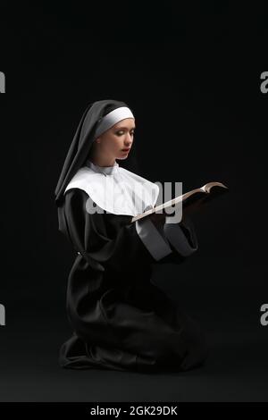 Jeune nonne avec la Bible sur fond sombre Banque D'Images