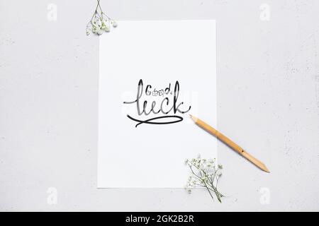 Papier avec texte BONNE CHANCE, stylo trempette et fleurs sur fond blanc Banque D'Images